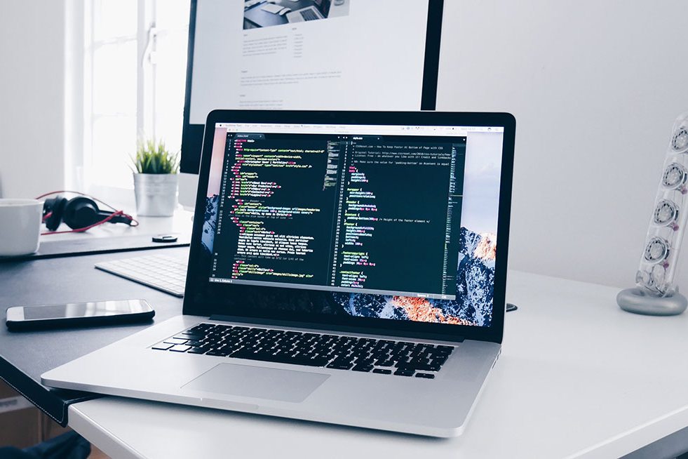 Laptop showing website code on a web designer’s desk