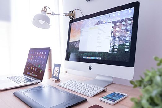 Designer’s desk with a desktop computer, laptop and drawing tablet