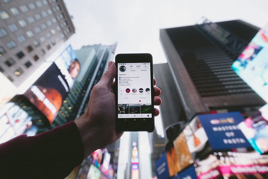 Hand holding a smartphone showing a business profile in a busy city