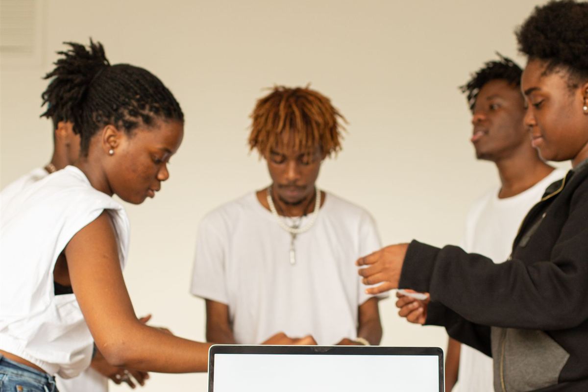 Young African team gathered around a laptop in an office