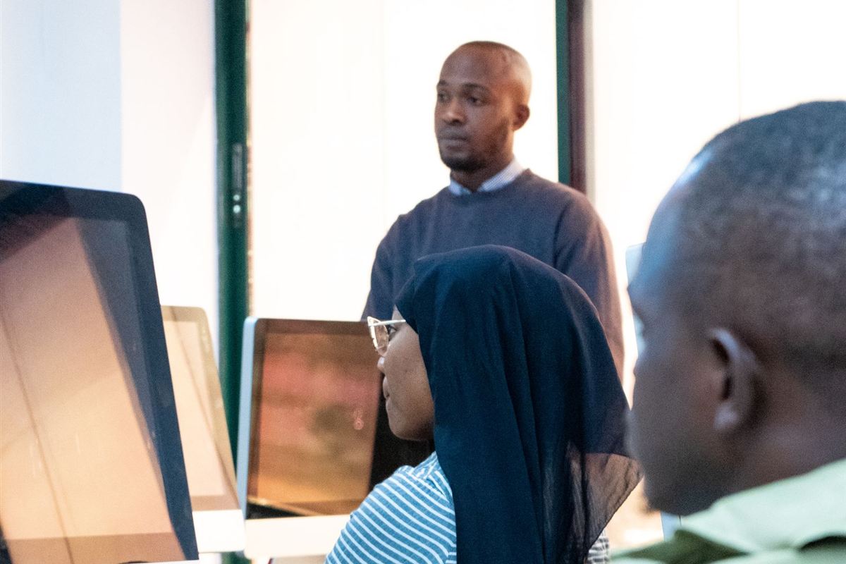 African trainer guiding learners in a computer lab
